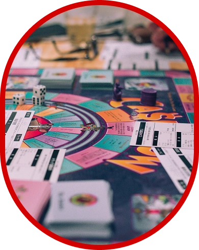 Giocatori che annotano i punteggi ed effettuano le mosse durante una serata dedicata ai giochi da tavolo con carte, dadi e un colorato tabellone da gioco.