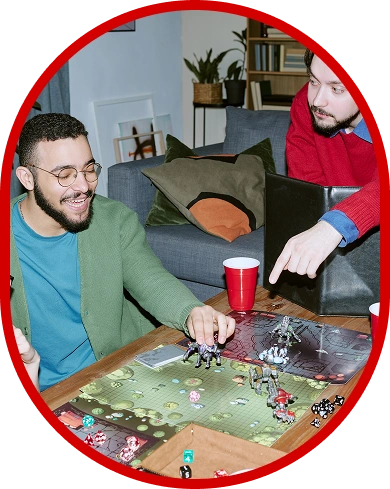 Amici che giocano a un gioco da tavolo fantasy con miniature, dadi e tabelloni durante una serata sociale dedicata ai giochi da tavolo a casa.